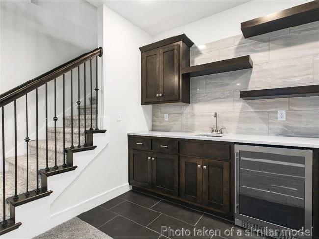 Indoor wet bar featuring beverage cooler, baseboards, decorative backsplash, stairs, and dark tile patterned floors