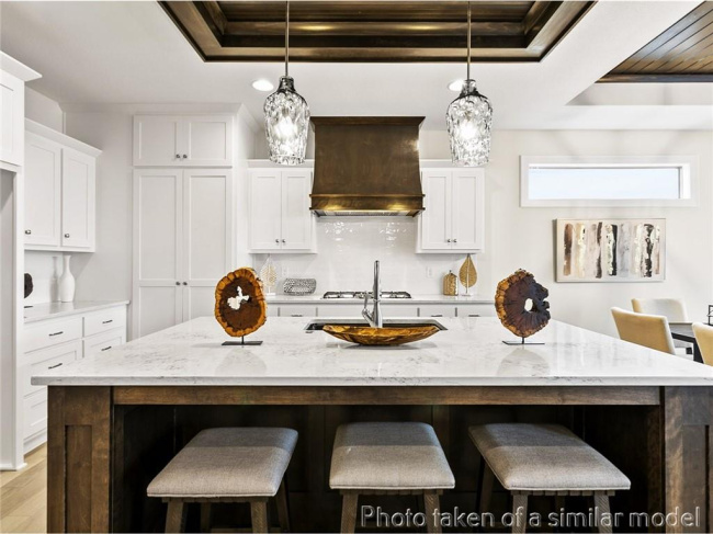 Kitchen with custom exhaust hood, a raised ceiling, a breakfast bar, light wood-style flooring, and white cabinetry