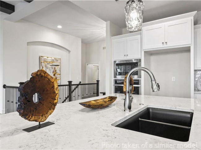 Kitchen with a sink, light stone countertops, recessed lighting, white cabinetry, and a chandelier