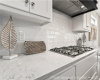 Kitchen with premium range hood, stainless steel gas cooktop, tasteful backsplash, and white cabinetry